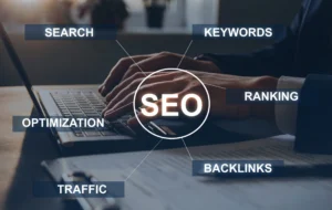 "SEO" in the middle over a picture of hands on a laptop keyboard. Text coming off the "SEO" read "keywords" "ranking" "backlinks" "traffic" "optimization" "search".