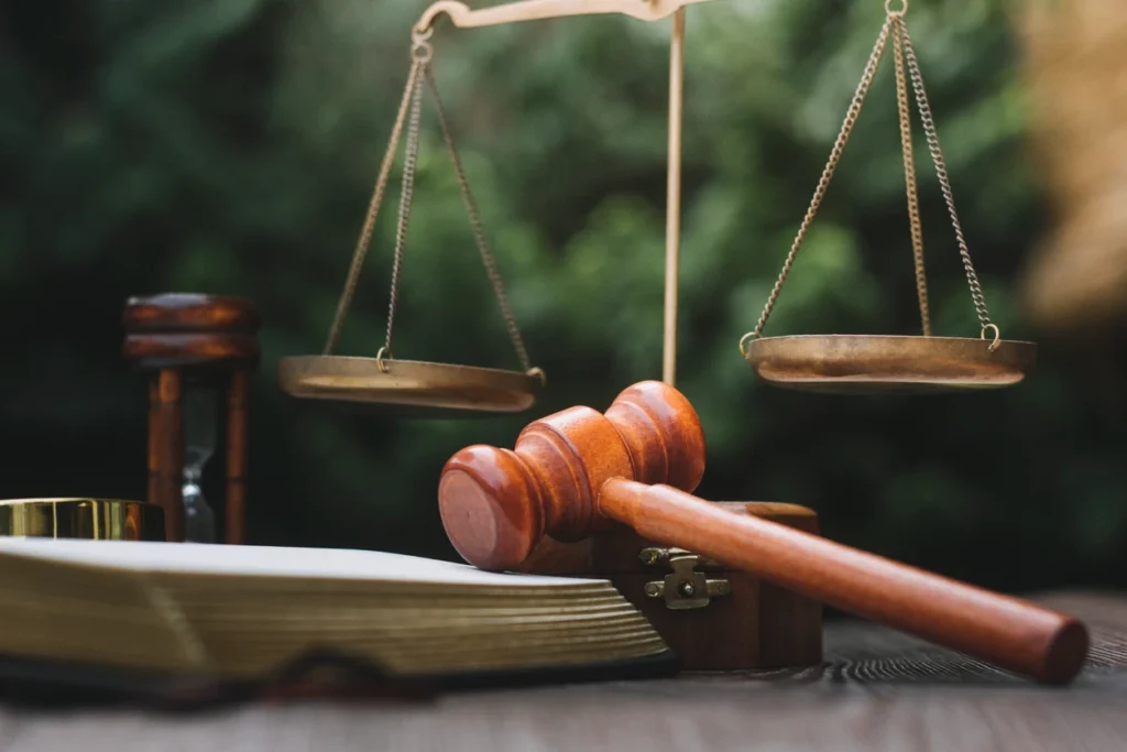 Judge gavel, justice scale, and law book sitting on a table. 