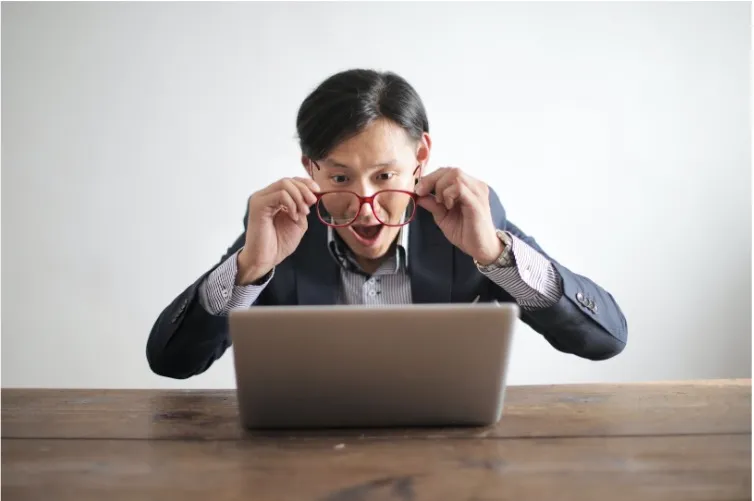 Man trying to read his screen using his glasses.